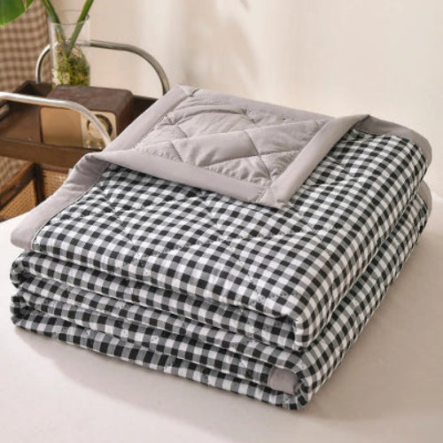 couverture à petits carreaux noirs et blancs pliée sur une table blanche