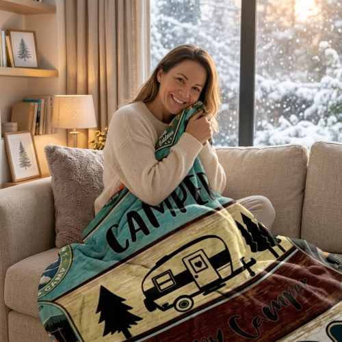couverture à motifs de camping dans les mains d'une femme souriante assise sur un sofa
