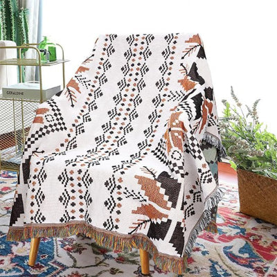 couverture blanc crème à motifs bohèmes noir et brun placée sur une chaise