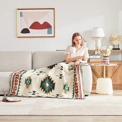 couverture de couleur blanc beige à motifs aztèques sur une femme assise sur un canapé