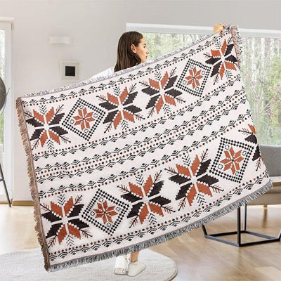 couverture sur fond blanc avec motifs géométriques ethniques noir et brun étendue dans les bras d'une femme