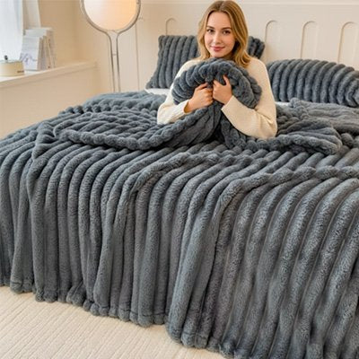 couverture gris foncé sur une femme sur le lit et qui tient une partie dans ses bras pour se recroqueviller