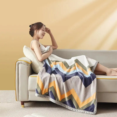 couverture dans les tons de beige et bleu sur une femme installée confortablement sur le canapé