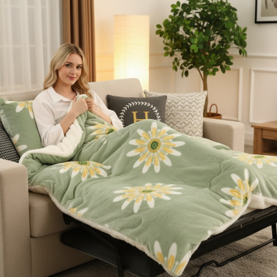 couverture polaire vert pâle avec marguerites blanches recouvrant une femme sur un sofa-lit 