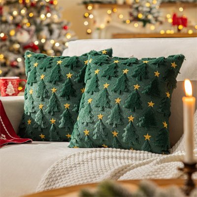 housse de coussin de coloration vert avec des étoiles et des sapins sur un sofa blanc dans un décor de noël