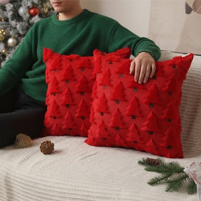 housse de coussin de couleur rouge avec des sapins en relief à côté d'un homme sur un canapé