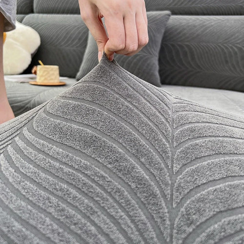 housse de canape d angle grise avec une main qui démontre l'élasticité du tissu