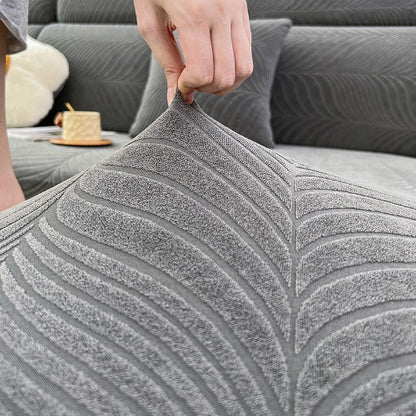 housse de canape d angle grise avec une main qui démontre l'élasticité du tissu