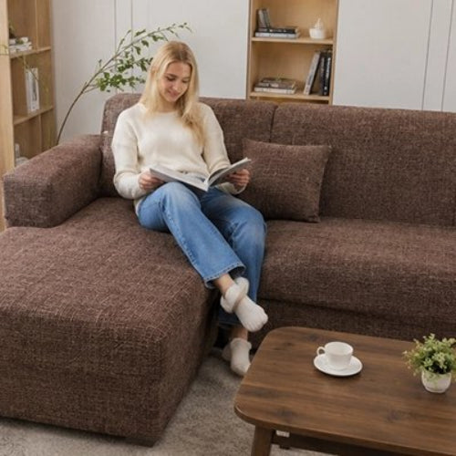 housse de canapé d'angle au ton marron sur laquelle une femme lit un livre