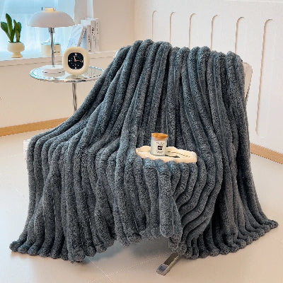 couverture de couleur grise déposée sur une chaise de salon dans un décor blanc