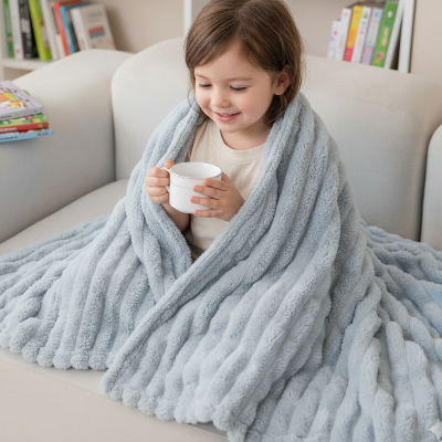 couverture enfant gris pâle sur une petite fille souriante assise sur le canapé tenant une tasse avec ses mains 